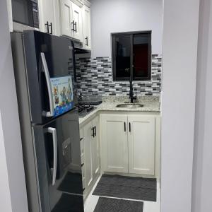 a kitchen with white cabinets and a black refrigerator at K&S luxury apartments in Montego Bay
