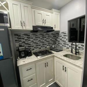 Una cocina con gabinetes blancos, un fregadero y un microondas. en K&S luxury apartments, en Montego Bay