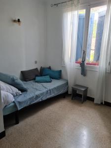 a bedroom with a bed with blue pillows and windows at Maison Gemenos in Gémenos
