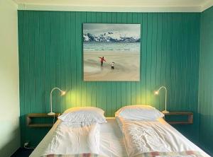 a bedroom with two beds and a painting on the wall at Nøtnes Midnattsol GuestHouse in Skrova