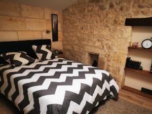 a bedroom with a black and white bed and a stone wall at APPARTEMENT COSY LIBOURNE in Libourne