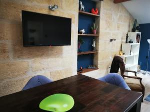 a dining room with a table and a tv at APPARTEMENT COSY LIBOURNE in Libourne