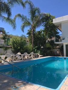 una piscina con sillas y palmeras en Hotel Kika, en São Gabriel