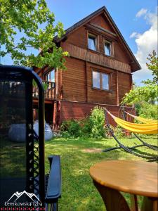 a wooden house with a table in front of it at Łemkowska Izba in Wysowa-Zdrój