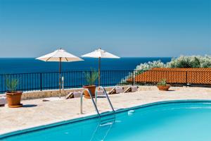 ein Pool mit zwei Sonnenschirmen und das Meer in der Unterkunft Holiday Park Olive Tree in Ulcinj