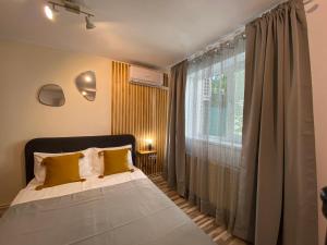 ein Schlafzimmer mit einem Bett mit gelben Kissen und einem Fenster in der Unterkunft Urseni Studio Apartment in Timişoara