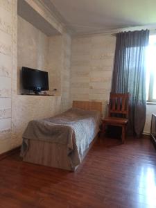 a bedroom with a bed and a tv and a chair at BBQ House in Dilijan