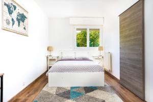 a white bedroom with a bed and a window at APPART PREMIUM DU LYS Balcon amenage Parking gratuit in Dammarie-lès-Lys