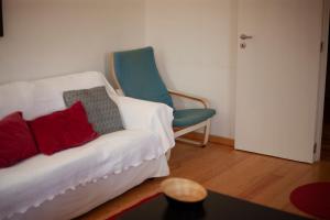 ein Wohnzimmer mit einer weißen Couch und einem blauen Stuhl in der Unterkunft Casa Romeu in Canedo de Basto