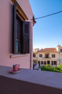 a cup of coffee sitting on the ledge of a balcony at Marthas DeLight Rooms in Chania Town