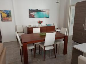 a dining room with a wooden table and white chairs at Residenza Tafuri in Salerno