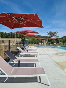 a row of lounge chairs with umbrellas next to a pool at Hébergement Insolite avec SPA - Foudrenlair in Bize-Minervois