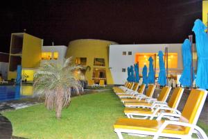 a row of chairs and blue umbrellas in front of a building at Kajaca Suite Hotel in Huacho