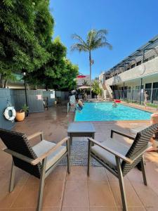 a swimming pool with two chairs and a table at Beachside Inn in Santa Barbara