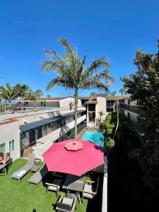 patio z różowym parasolem i basenem w obiekcie Beachside Inn w mieście Santa Barbara