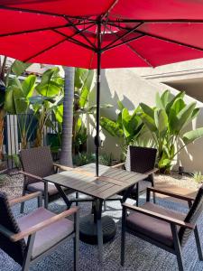 a picnic table and chairs with a red umbrella at Beachside Inn in Santa Barbara