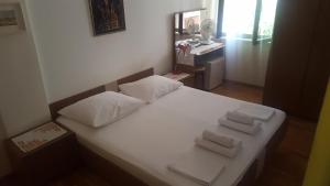 a white bed with three folded towels on it at Rooms and Apartments Roza in Portorož