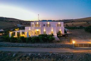 a large white house at night with the lights on at Levanta guesthouse in Schinoussa