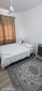 ein Schlafzimmer mit einem weißen Bett und einem Teppich in der Unterkunft Aida Homestay in Kuala Terengganu