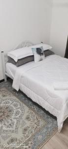 ein großes Bett mit weißen Laken und Kissen darauf in der Unterkunft Aida Homestay in Kuala Terengganu + 3 Fotos