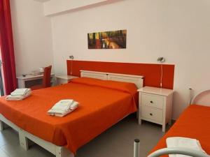 サンタ・クローチェ・カメリーナにあるColori Della Sicilia Guest Houseのベッドルーム1室(オレンジのシーツを使用したベッド2台付)