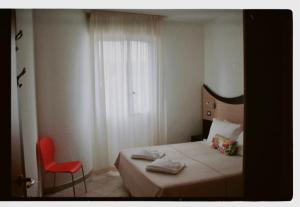 1 dormitorio con 1 cama y 1 silla roja en Tropicana Residence en Lido degli Estensi