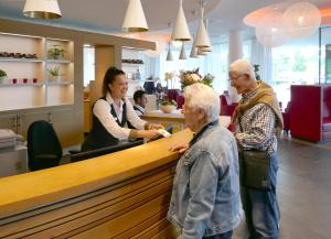 Hotel Udens Duyn في أودن: رجلان وامرأة يقفان عند كونتر في محل