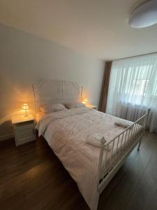 sypialnia z białym łóżkiem z dwoma stołami i oknem w obiekcie APARTMENTS IN THE CITY CENTER BIRŽAI Vytauto g22 w mieście Birże