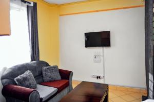 a living room with a couch and a tv on a wall at Attic Place South B in Nairobi