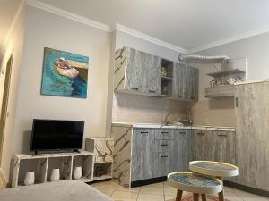 a kitchen with wooden cabinets and a tv in a room at Lungomare Rei's Apartment in Durrës
