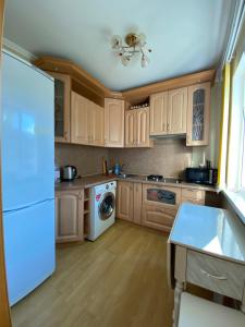 a kitchen with wooden cabinets and a white refrigerator at Apartment on Abazgaa in Gagra