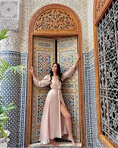a woman is standing in front of a door at Riad Fes Nass Zmane in Fez