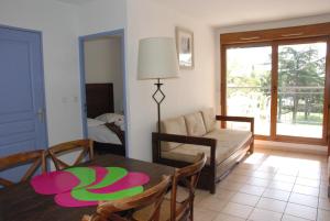 a living room with a table and a couch at UZES APPART HOTEL Résidence Le Mas des Oliviers in Uzès