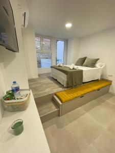 1 dormitorio con 1 cama grande y banco amarillo en Merkat Center Alicante, en Alicante