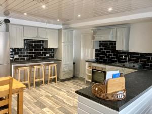 a large kitchen with white cabinets and black tiles at A wave from it all in Blackpool