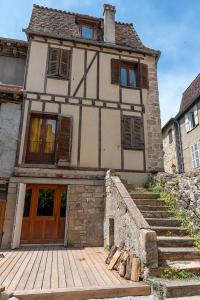 una vecchia casa con un passaggio in legno di fronte di Logis face à l'Abbatiale a Beaulieu-sur-Dordogne