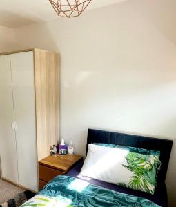 a bedroom with a bed and a wooden cabinet at 5min Drive to Luton Airport, 2 Train Stations & Motorway - FREE PARKING - LATE CHECK OUT 11AM - Quiet & Peaceful Location with a relaxing Garden - ONLY 25min drive to North LONDON - FREE WIFI in Luton