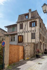 una vecchia casa con un cancello in legno di fronte di Logis face à l'Abbatiale a Beaulieu-sur-Dordogne