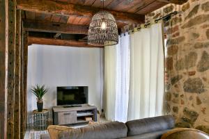 een woonkamer met een bank en een televisie bij Logis face à l'Abbatiale in Beaulieu-sur-Dordogne