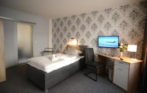 a bedroom with a bed and a desk and a television at Landhotel Kussmann in Wrexen