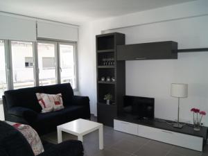 uma sala de estar com um sofá preto e uma televisão em Urpa Apartaments em Llançà