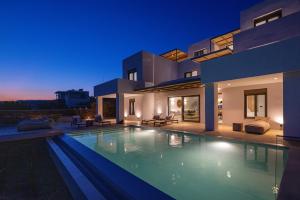 提诺斯Blue Gres Villa Tinos的夜晚带泳池的别墅