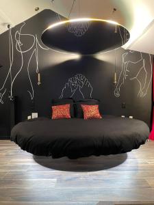 - une chambre avec un lit aux murs noirs et des dessins sur le mur dans l'établissement Luxe and Spa, à Condé-Sainte-Libiaire