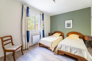 two beds in a room with a chair and a window at Le Nadadou par Dodo à Cassis in Cassis