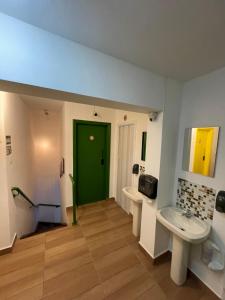 a bathroom with two sinks and a green door at Jardins Village Hostel - Jardim Paulista in Sao Paulo