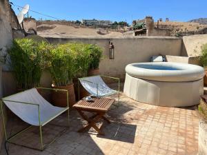 een patio met een bad, 2 stoelen en een tafel bij La Maison Maure in Fès