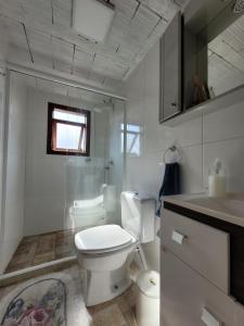 a white bathroom with a toilet and a sink at Casa Cabana in Canela