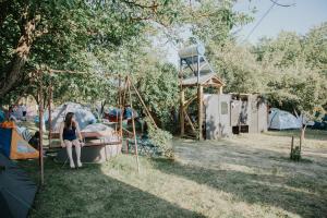 a woman sitting on a swing in a park at Secret Garden Camping in Bontida