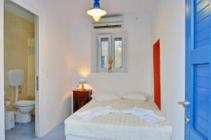 a white bedroom with a bed and a toilet at Katerina Rooms in Adamantas
