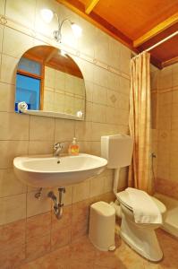 a bathroom with a sink and a toilet and a mirror at Katerina Rooms in Adamas